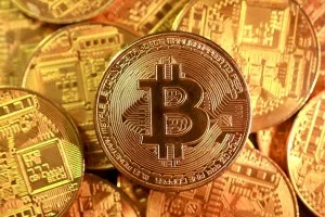 Moeda dourada de Bitcoin em destaque sobre um fundo de gráficos financeiros digitais em tons de azul e verde, com luzes cinematográficas.