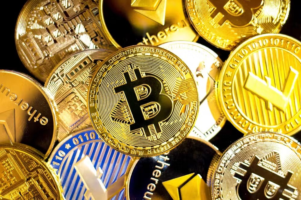 Uma mão segura um smartphone exibindo gráficos de criptomoedas, enquanto ao fundo, embaçado, bandeiras dos EUA e Irã se entrelaçam. A cena sugere vigilância financeira.