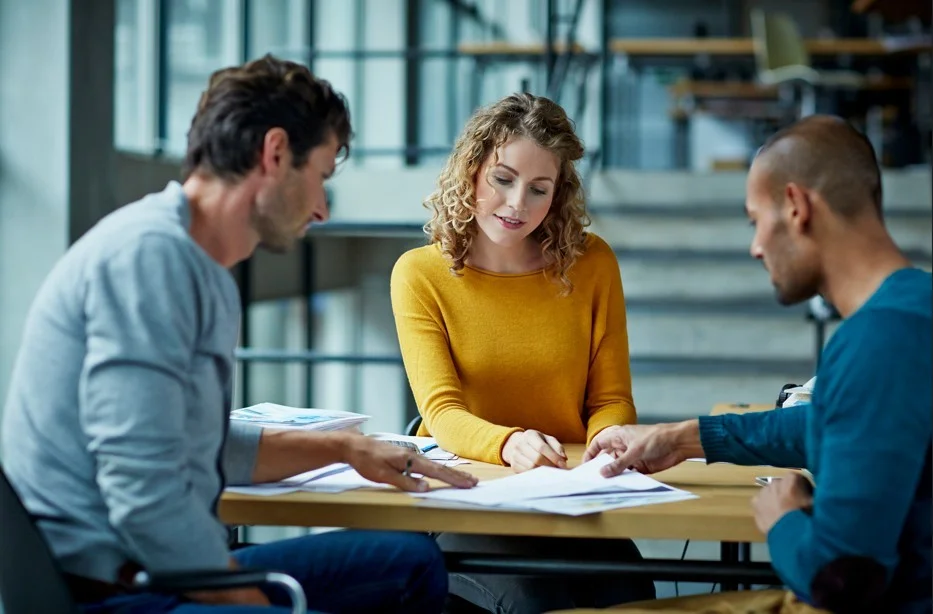 Executivos diversos em uma reunião de negócios colaborativa e objetiva na Holanda, com arquitetura moderna e canais ao fundo, simbolizando eficiência e inovação.