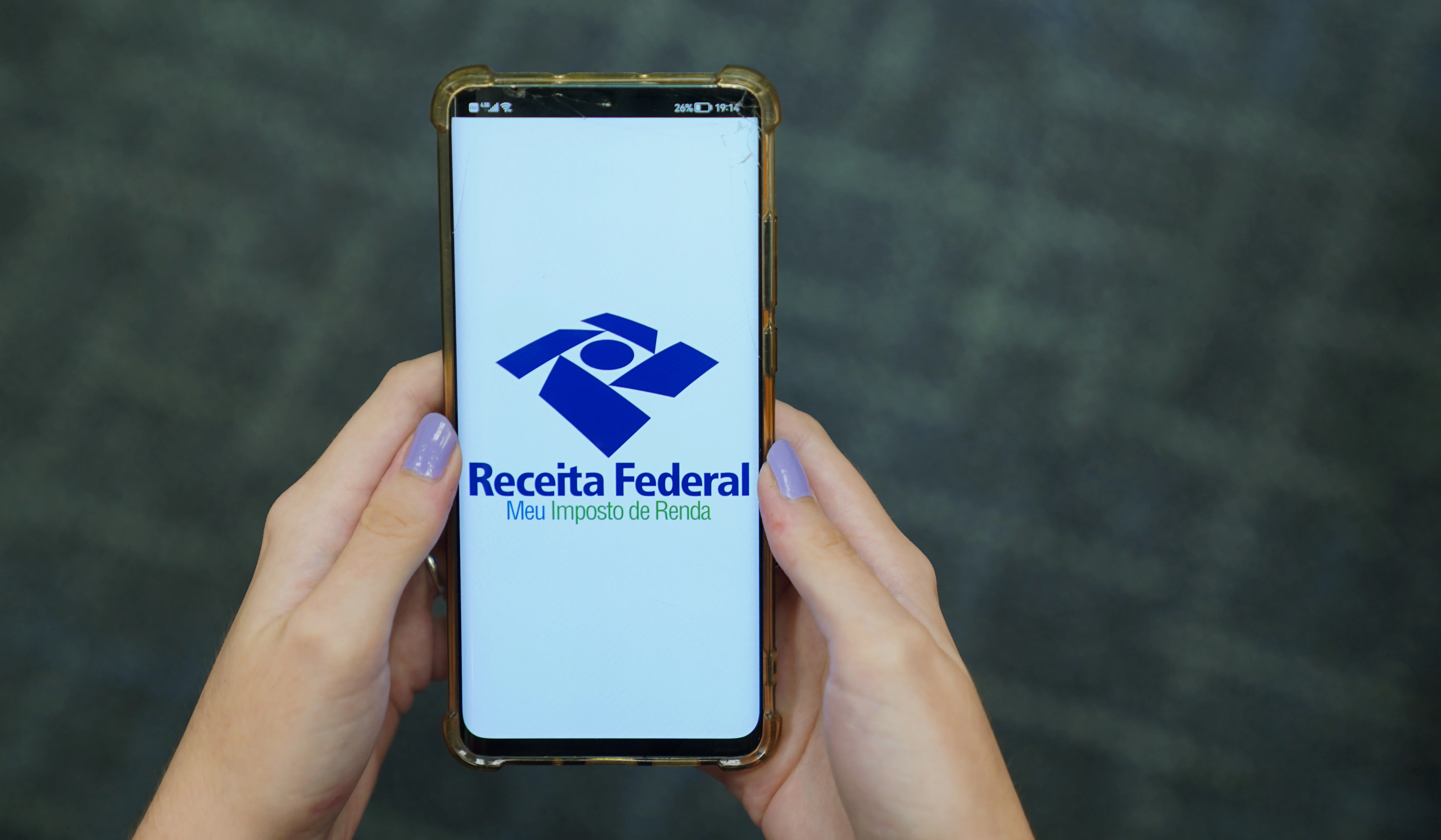 Close de um teclado de computador moderno com uma lupa focada sobre a tecla 'Enter', simbolizando a auditoria e revisão de documentos fiscais digitais.
