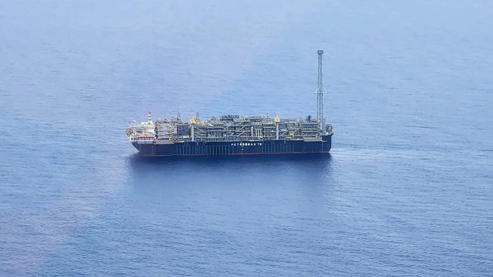 Uma plataforma de petróleo offshore da Petrobras ao amanhecer, com um navio-tanque ao fundo, simbolizando a exportação e os desafios tributários. O céu tem tons dourados e azuis.
