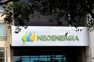 Linhas de transmissão de energia elétrica atravessando um campo verdejante sob o pôr do sol, representando a infraestrutura da Neoenergia.