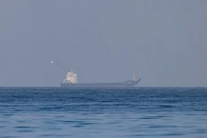 Uma vista aérea cinematográfica do Estreito de Hormuz com navios petroleiros gigantes navegando entre montanhas áridas e águas azuis profundas sob um pôr do sol dourado.