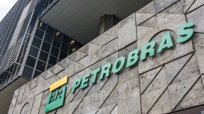 Gráfico financeiro de velas verdes e vermelhas mostrando a alta das ações da Petrobras (PETR4) com barris de petróleo em segundo plano, simbolizando a valorização da commodity e seu impacto no mercado de ações.